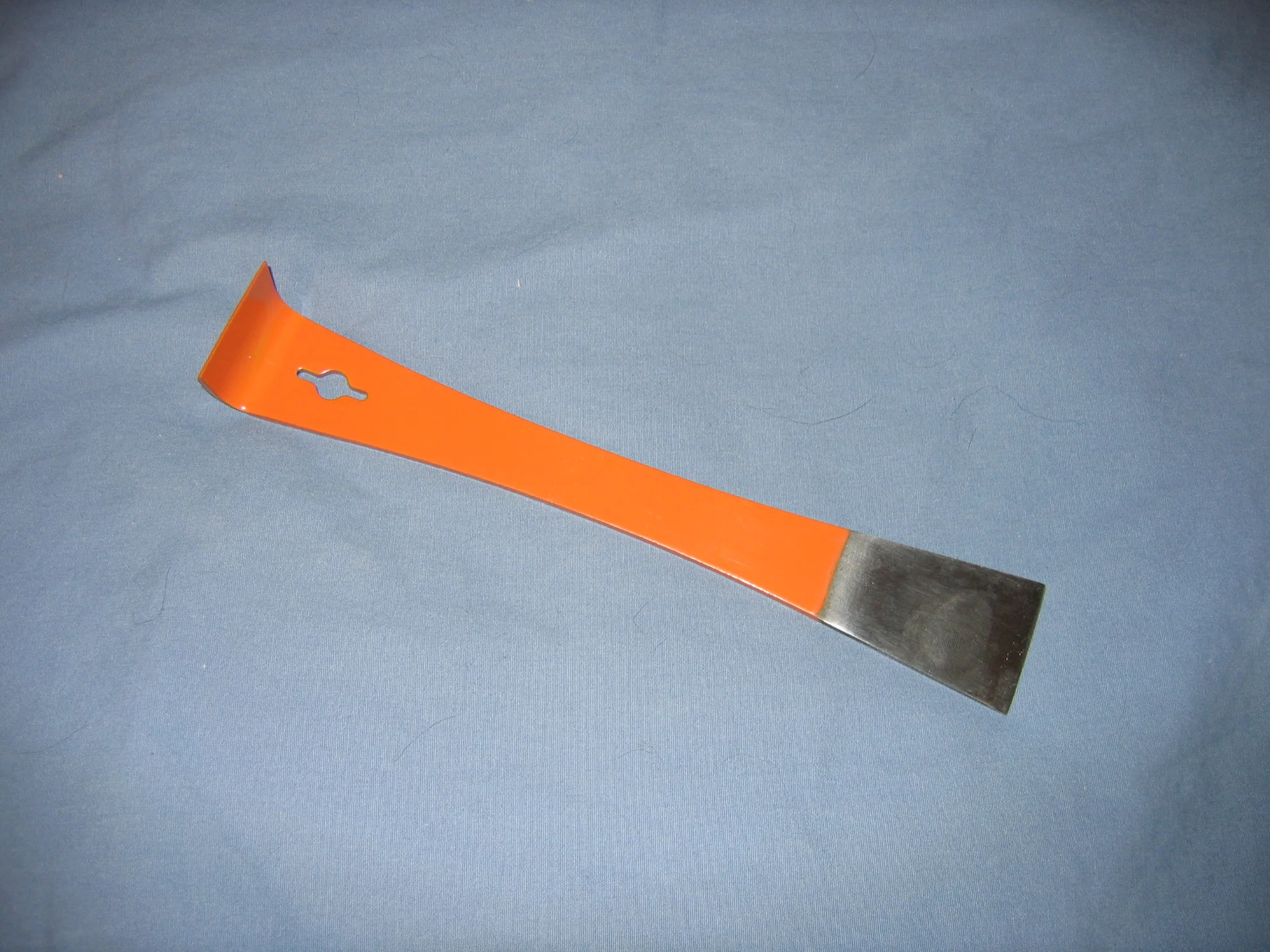 Een oranje imkersbeitel met aan de ene kant een brede schraper en aan de andere kant een gebogen wrikhaak